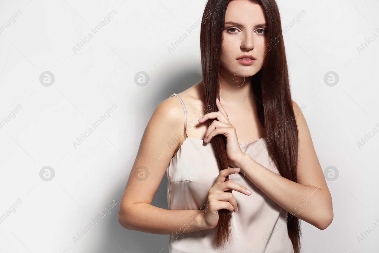 Photo of Portrait of beautiful young woman with healthy strong hair on light gray background, space for text