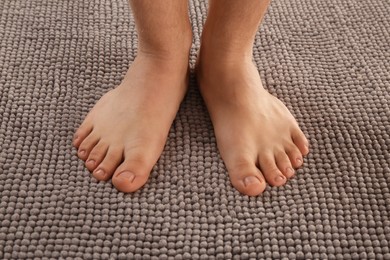 Photo of Man standing on soft grey bath mat, closeup