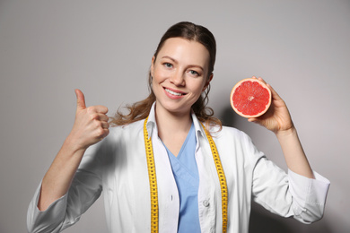 Nutritionist with grapefruit on light grey background