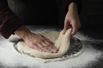 Photo of Woman kneading pizza dough at table, closeup