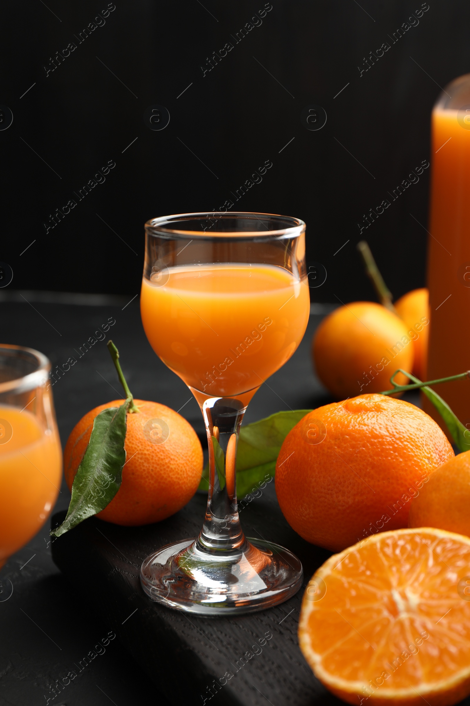 Photo of Tasty tangerine liqueur and fresh fruits on black table