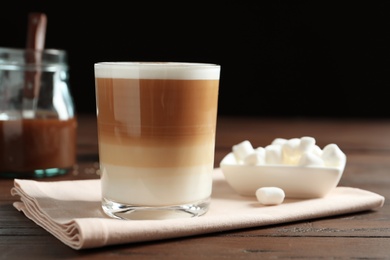 Photo of Glass with delicious caramel latte on table