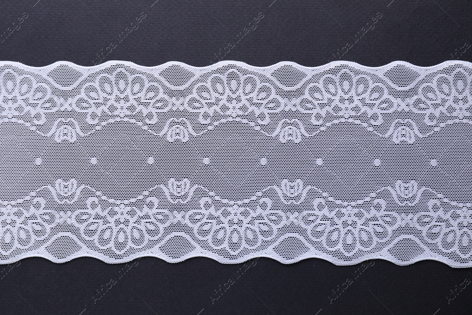 Photo of White lace on black background, top view