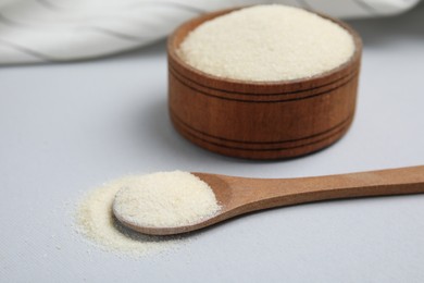 Photo of Wooden bowl and spoon with gelatin powder on light grey background