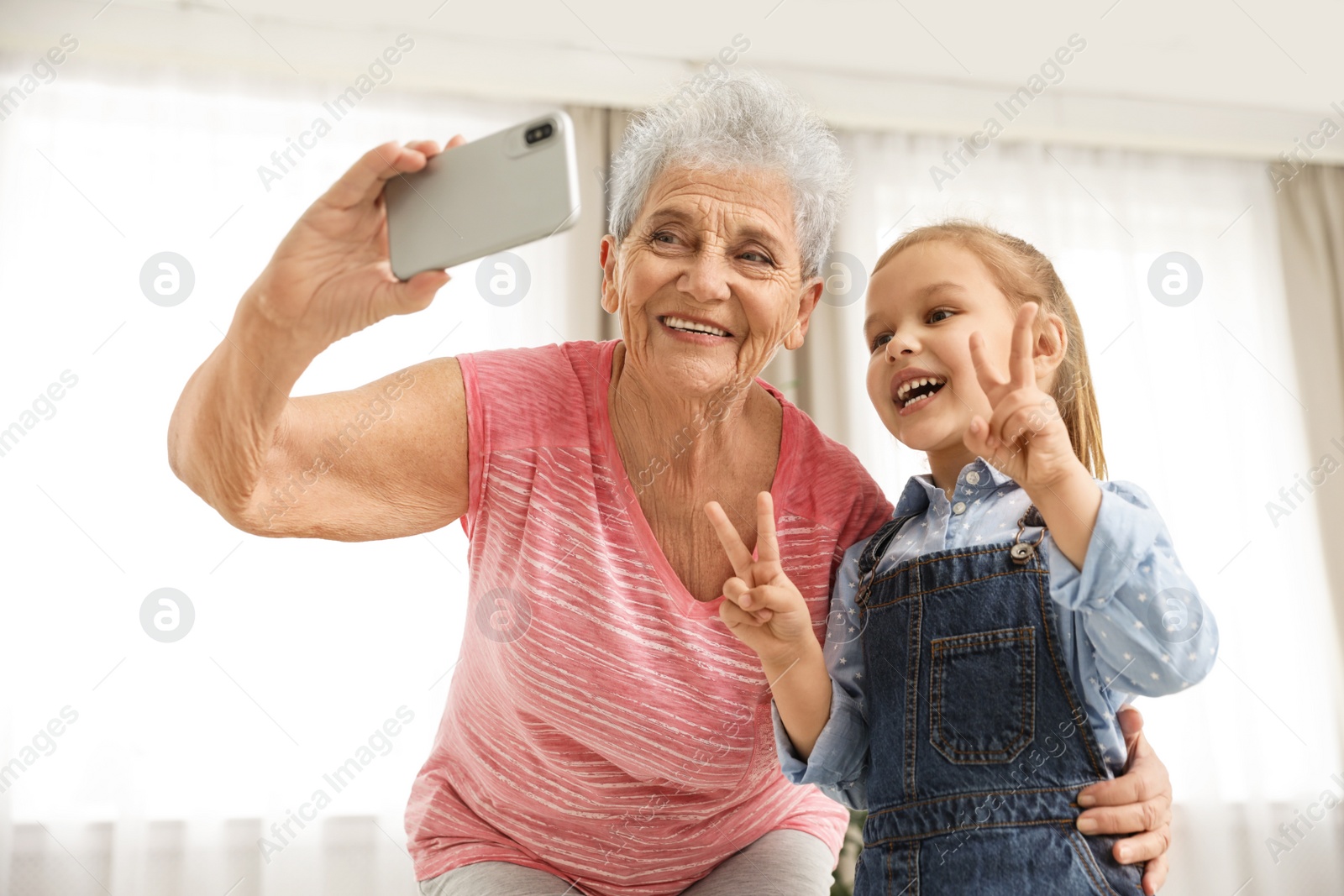 Photo of Cute girl and her grandmother taking selfie  at home