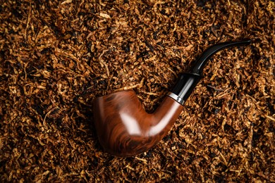 Photo of Smoking pipe on pile of tobacco, top view