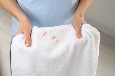 Photo of Woman holding terry towel with makeup spot indoors, closeup