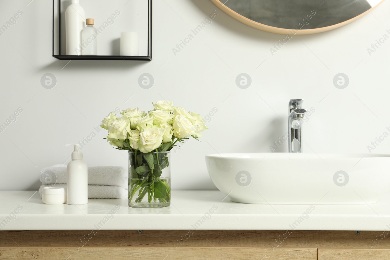 Photo of Beautiful roses and bath accessories near sink in bathroom