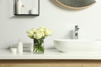 Photo of Beautiful roses and bath accessories near sink in bathroom