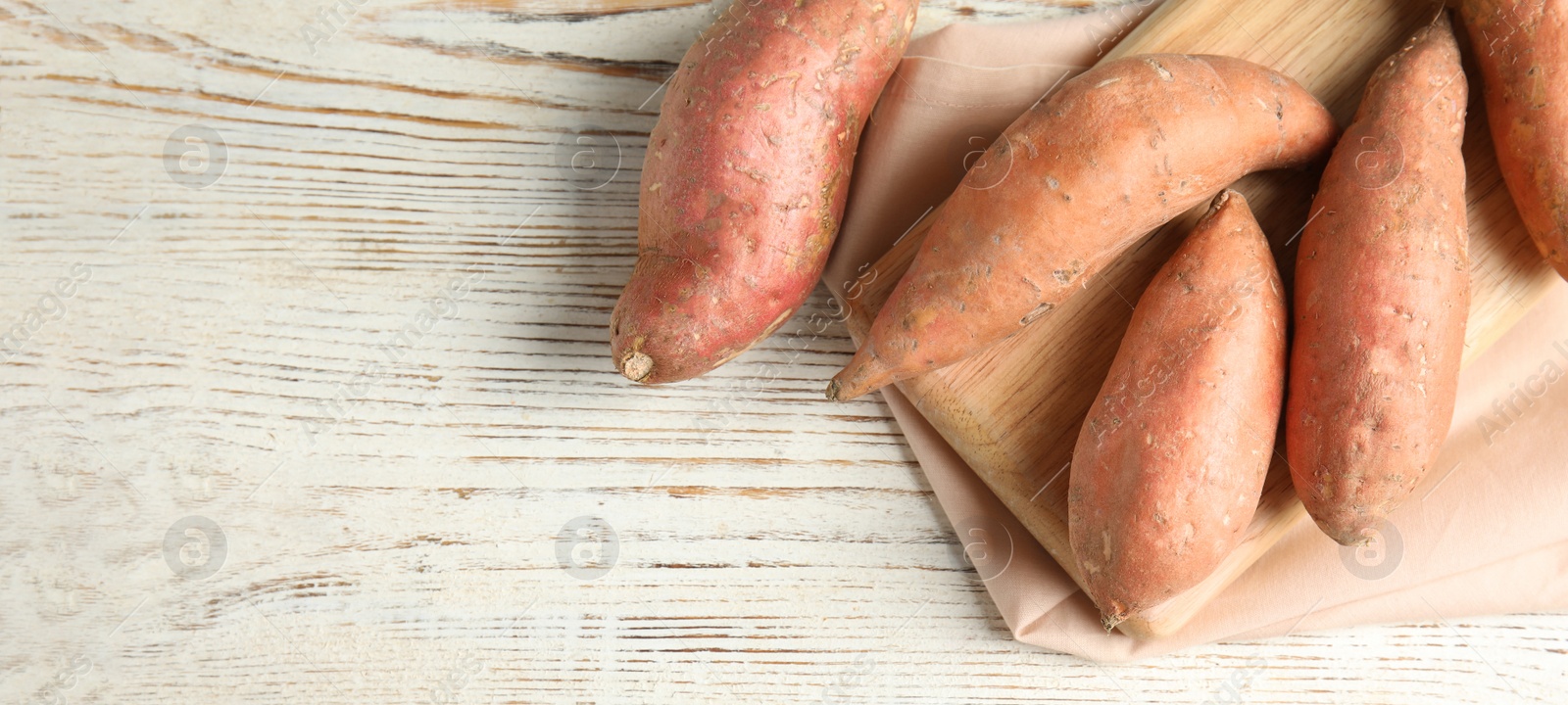 Image of Sweet potatoes and space for text on white wooden table, top view. Banner design