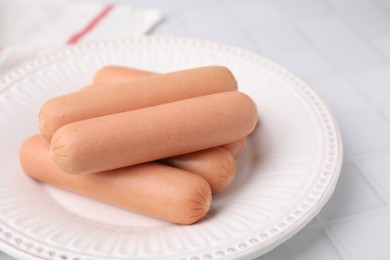 Photo of Delicious boiled sausages on white tiled table, closeup