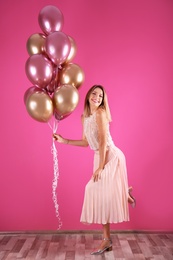 Young woman with air balloons near color wall