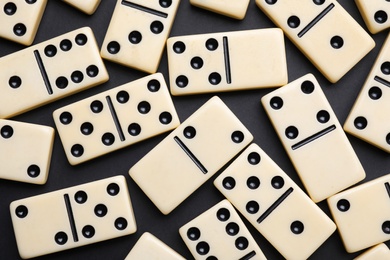 Photo of Classic domino tiles on black background, flat lay