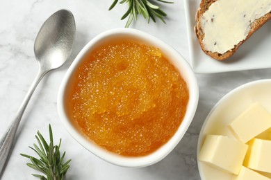 Photo of Fresh pike caviar in bowl, bread, rosemary and butter on white marble table, flat lay