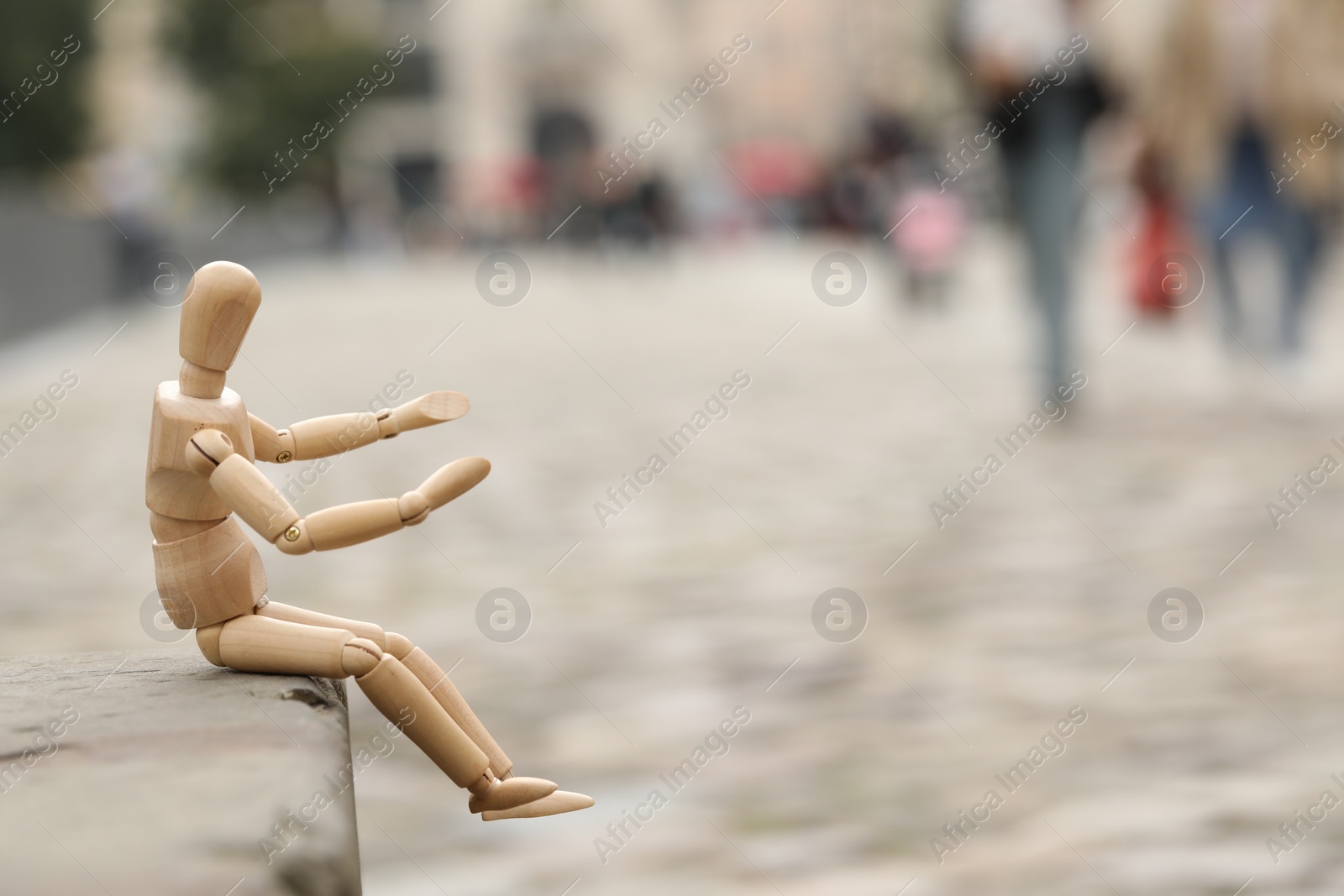 Photo of Wooden human figure sitting on curb outdoors, space for text