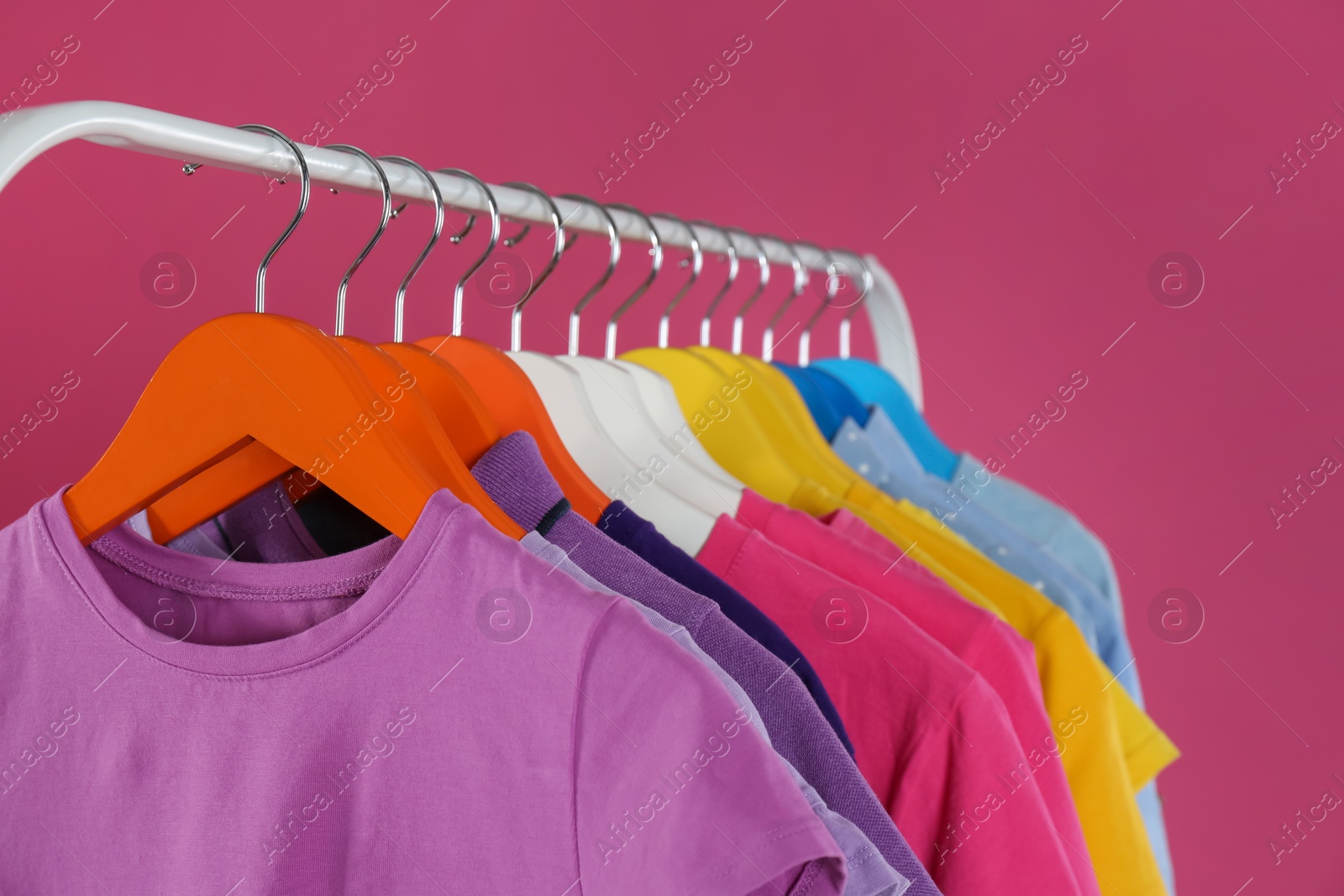 Photo of Rack with stylish children clothes on pink background, closeup