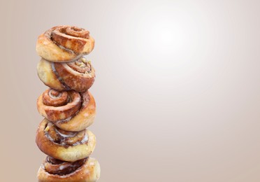 Image of Cinnamon rolls balancing on light greyish brown background, space for text
