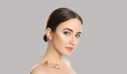 Image of Young woman with beautiful tattoo of flowers and butterfly on light grey background. Banner design
