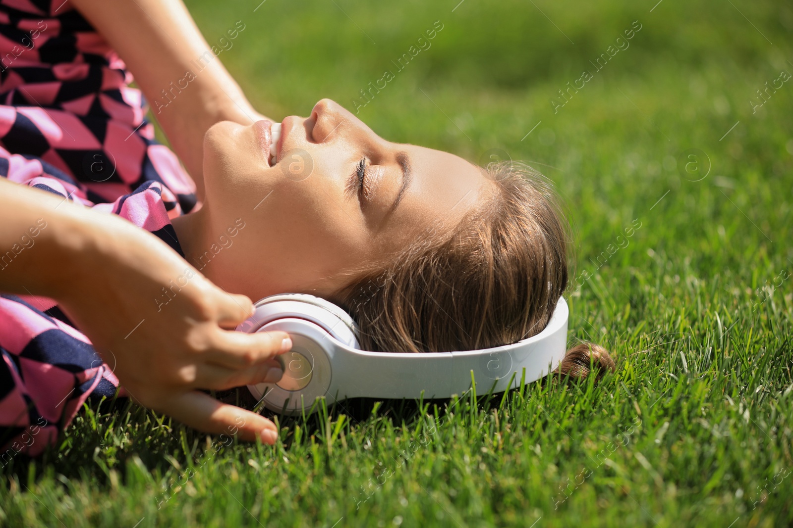 Photo of Young woman with headphones listening to music in park. Space for text