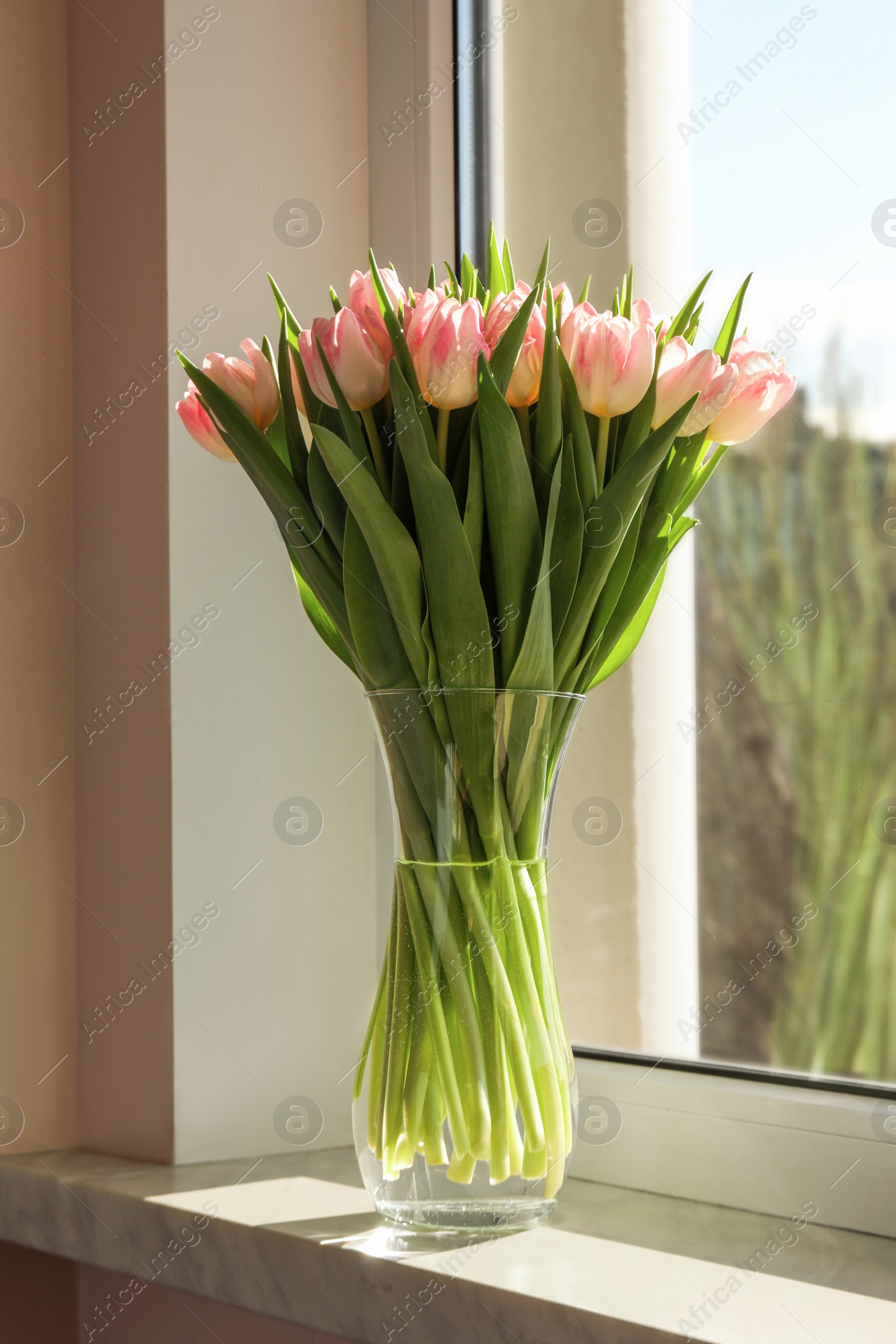 Photo of Spring is coming. Bouquet of beautiful tulip flowers in glass vase on windowsill indoors