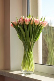 Spring is coming. Bouquet of beautiful tulip flowers in glass vase on windowsill indoors