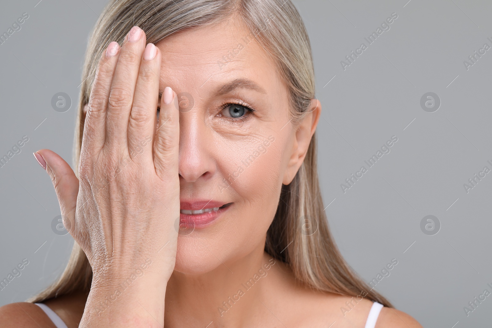 Photo of Beautiful mature woman with healthy skin on gray background