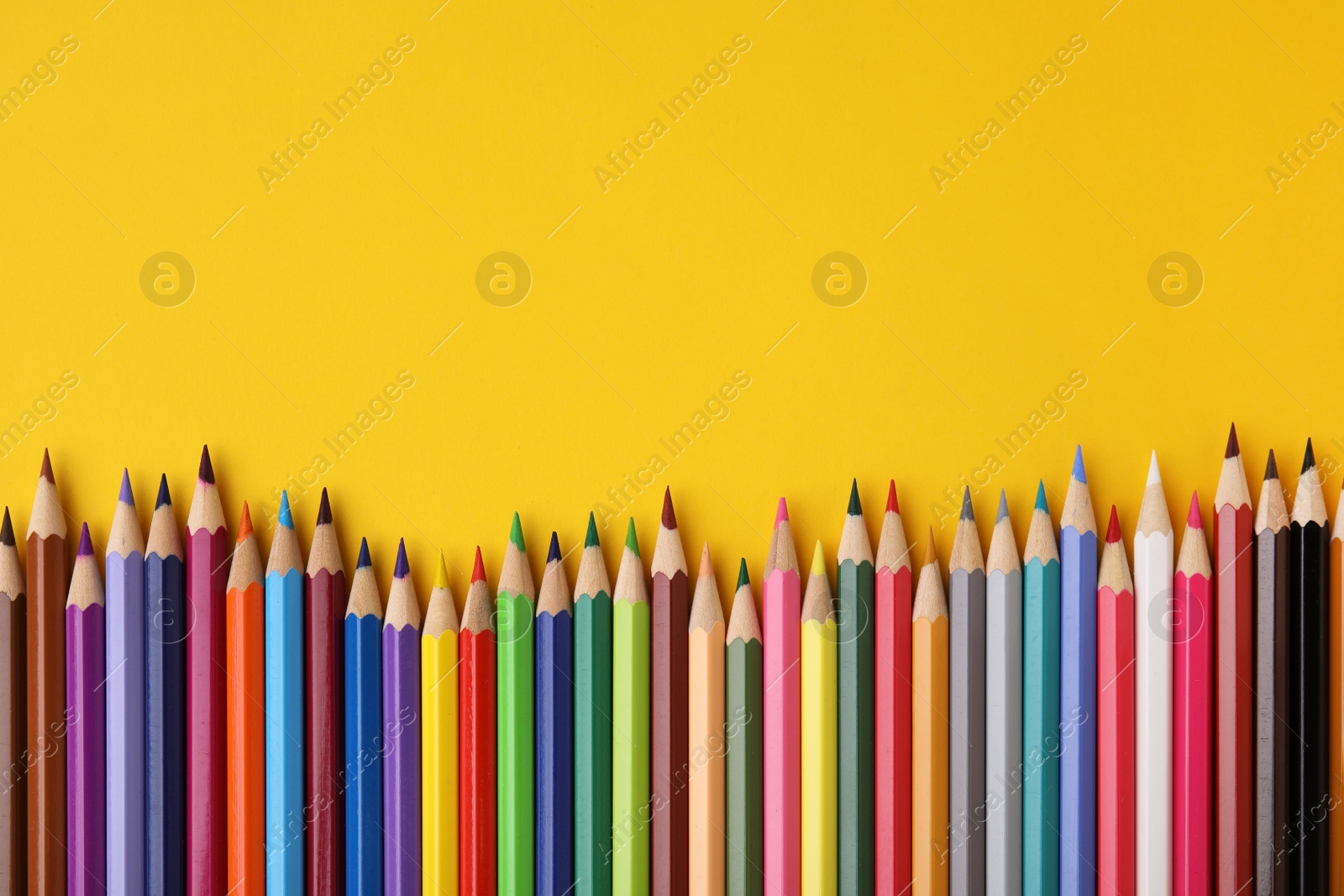 Photo of Colorful wooden pencils on yellow background, flat lay. Space for text