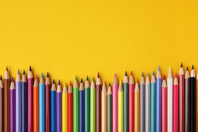 Photo of Colorful wooden pencils on yellow background, flat lay. Space for text