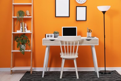 Workplace with laptop, stationery on desk and chair in home office