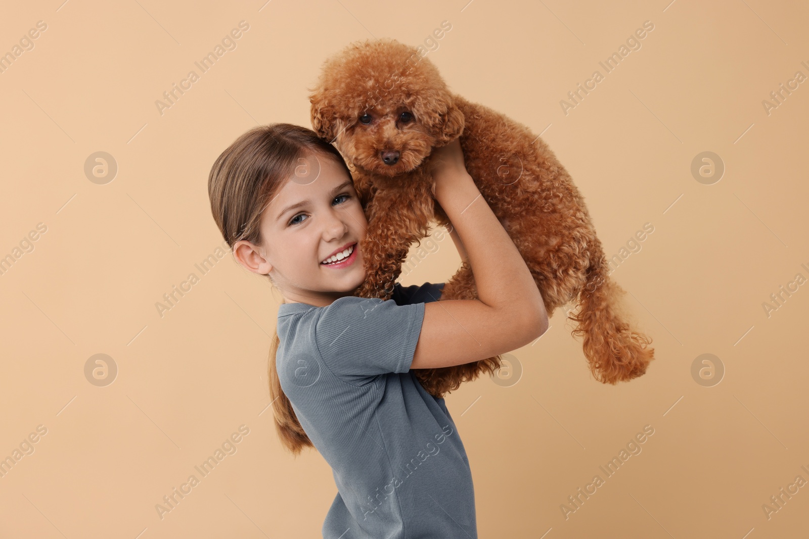 Photo of Little child with cute puppy on beige background. Lovely pet