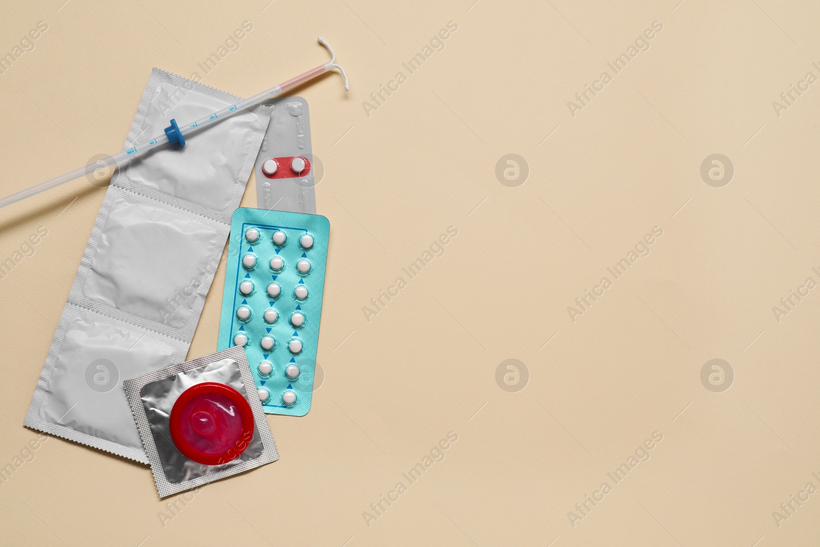 Photo of Contraception choice. Pills, condoms and intrauterine device on beige background, flat lay. Space for text