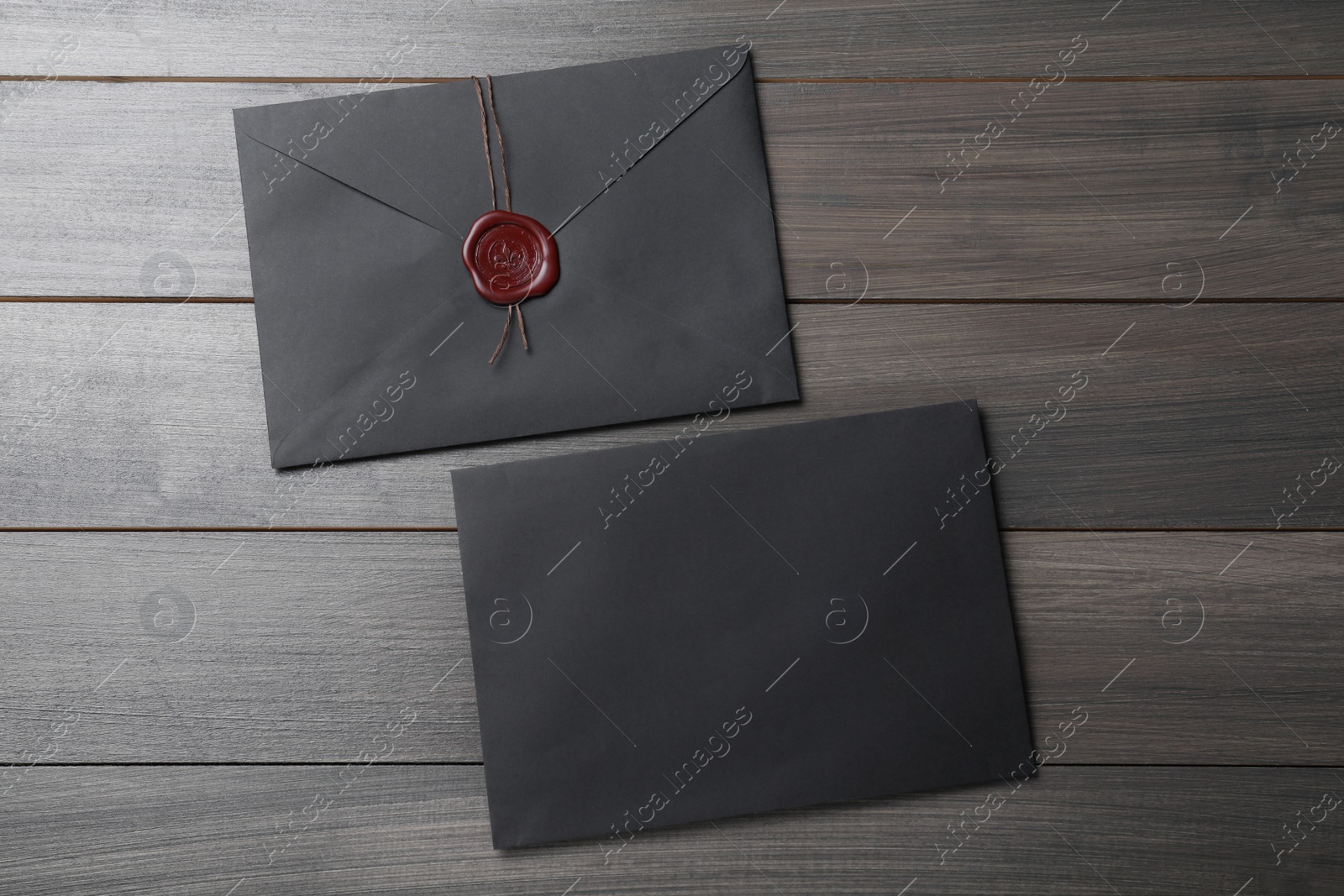 Photo of Black envelopes with wax seal on wooden background, flat lay