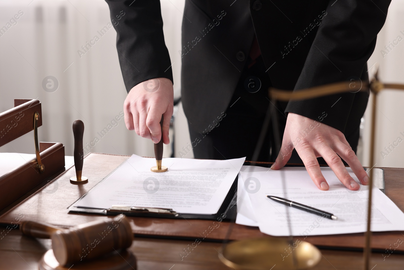 Photo of Notary stamping document at wooden table in office, closeup