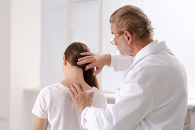 Photo of Professional orthopedist examining patient's neck in clinic
