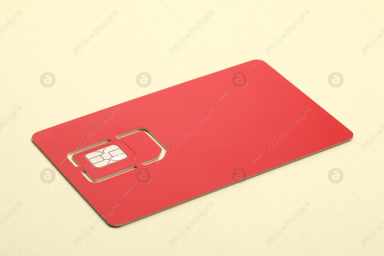Photo of Modern red SIM card on beige background, closeup