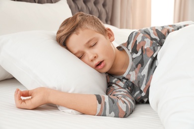 Cute tired boy sleeping in comfortable bed