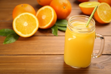 Photo of Delicious orange juice on wooden table. Space for text