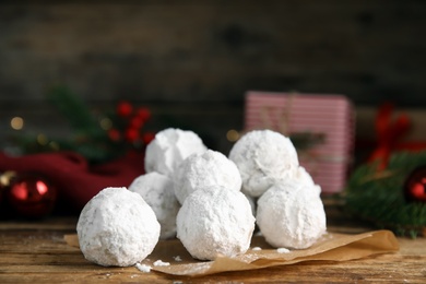 Photo of Tasty snowball cookies and Christmas decorations on wooden table, closeup