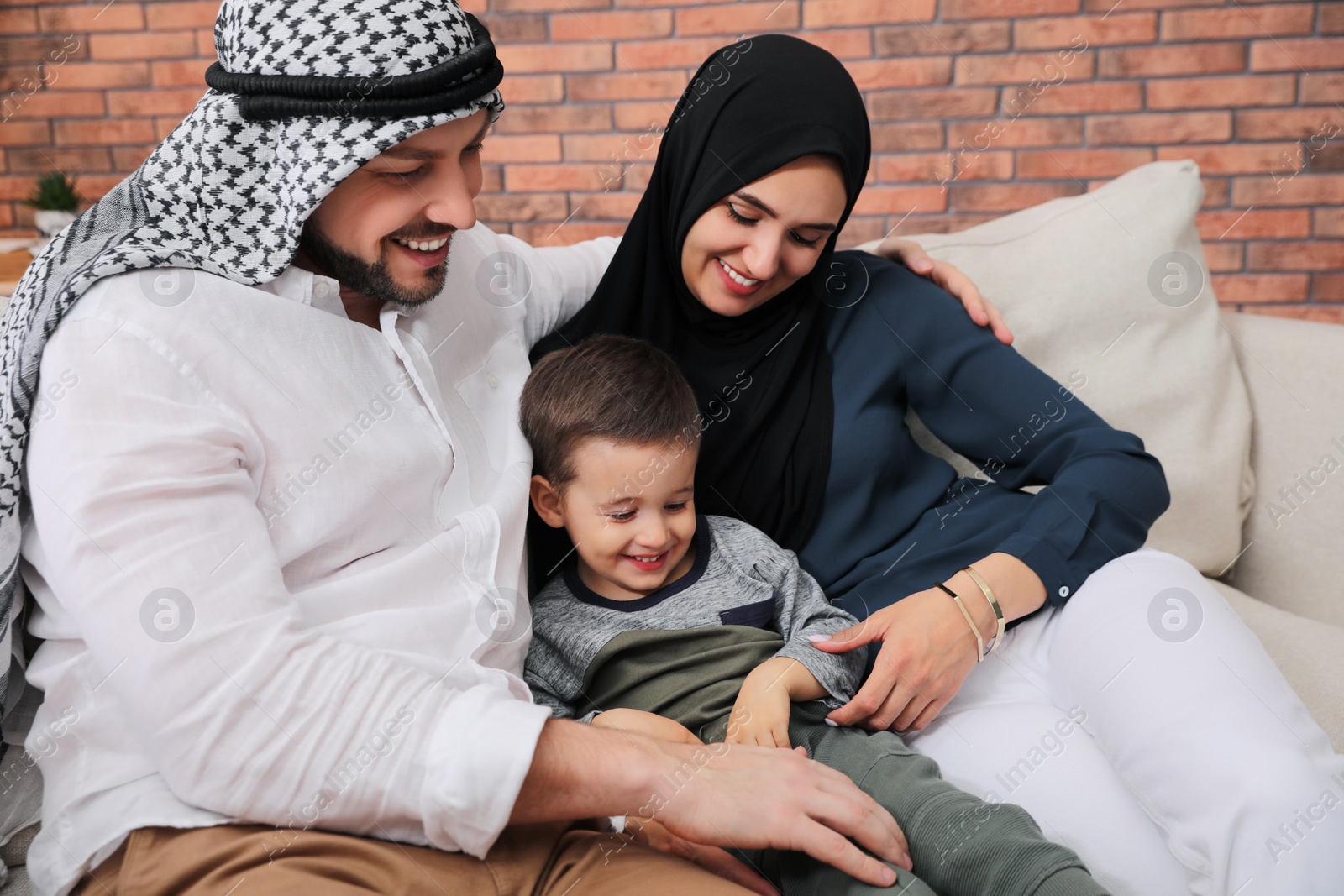 Photo of Happy Muslim family spending time together on sofa at home