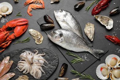 Fresh fish and different seafood on black table, flat lay