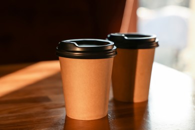 Photo of Paper coffee cups on wooden table in cafe
