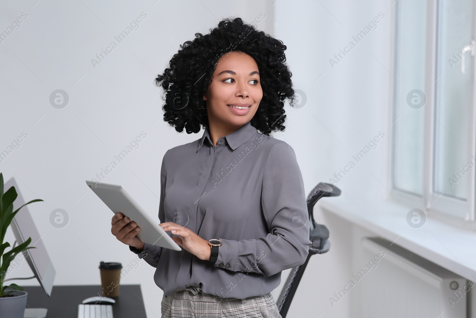 Photo of Smiling young businesswoman using tablet in office