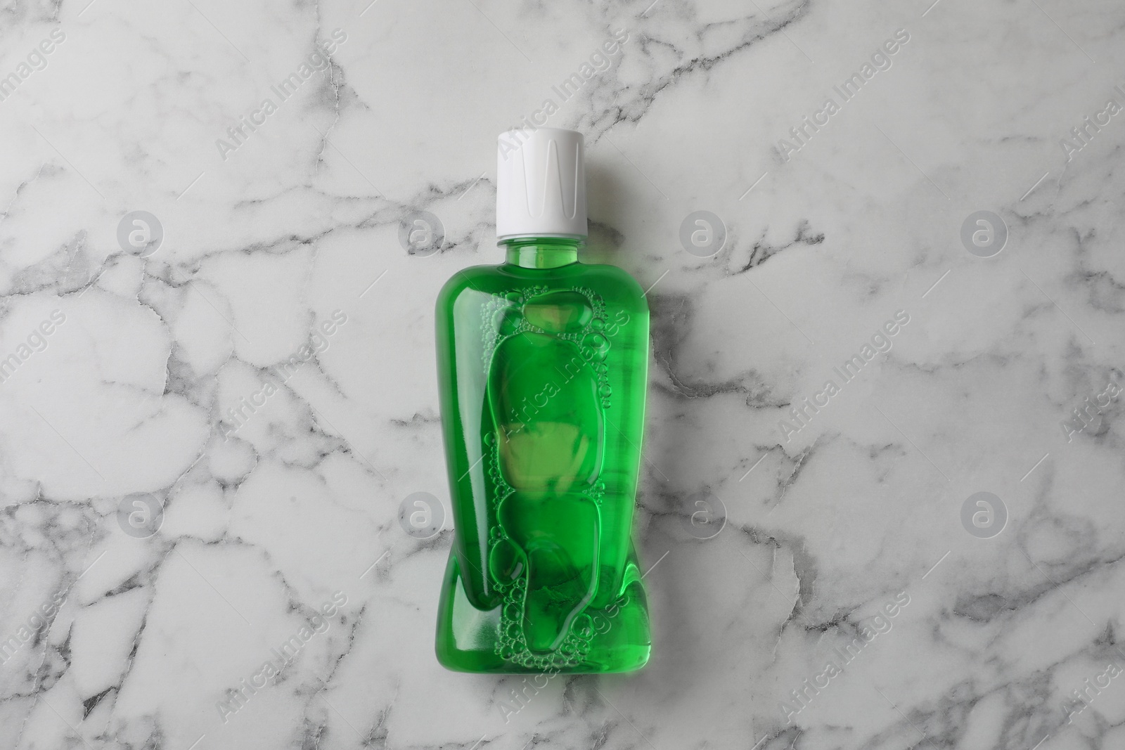 Photo of Fresh mouthwash in bottle on white marble table, top view