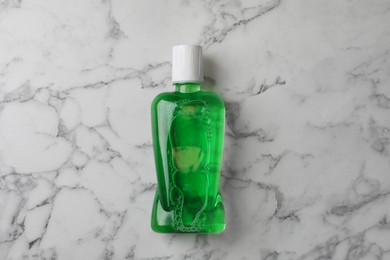 Fresh mouthwash in bottle on white marble table, top view