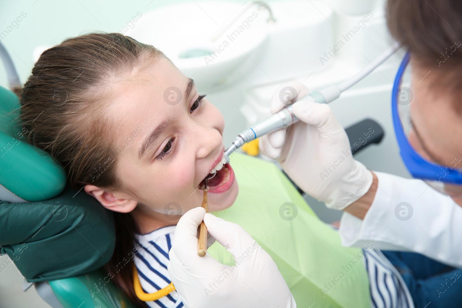 Photo of Professional dentist working with little patient in modern clinic