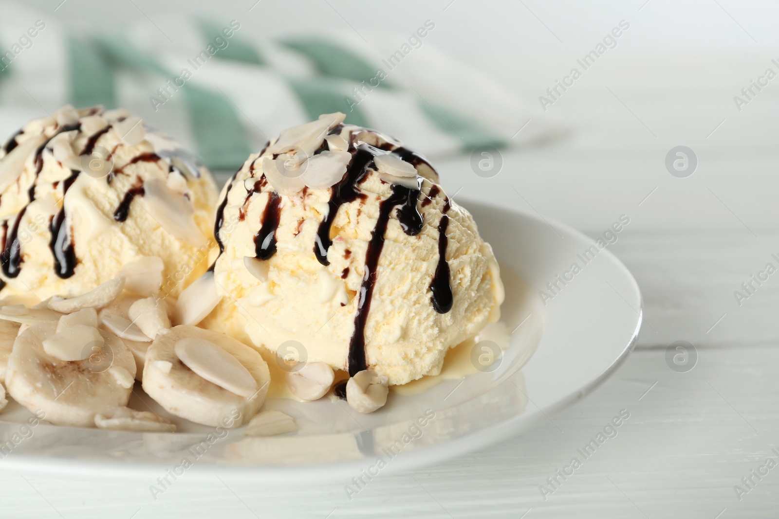 Photo of Delicious banana ice cream with toppings on white wooden table, closeup