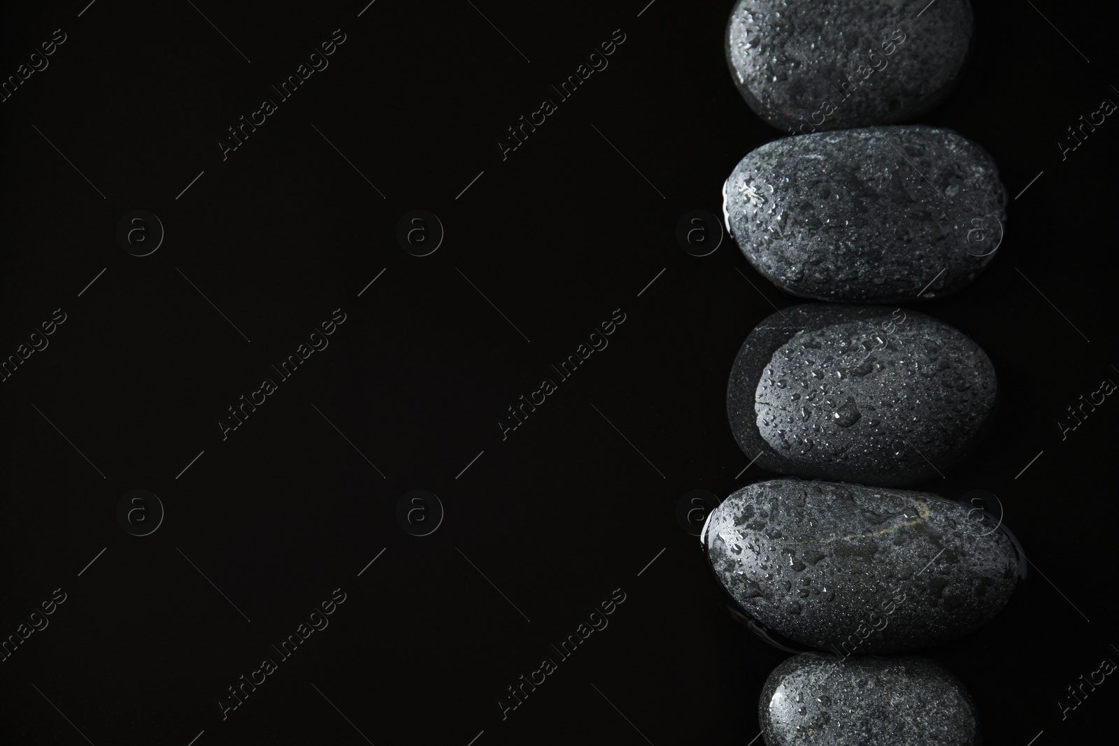 Photo of Stones in water on black background, flat lay with space for text. Zen lifestyle