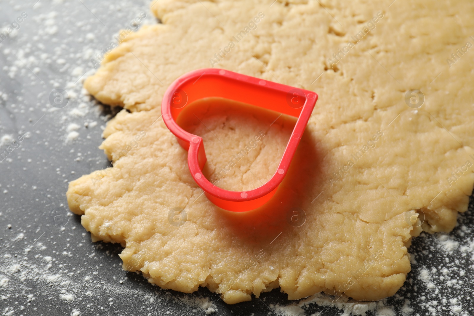 Photo of Making shortcrust pastry. Raw dough and cookie cutter on grey table