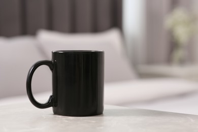 Photo of Black ceramic mug on table indoors. Mockup for design