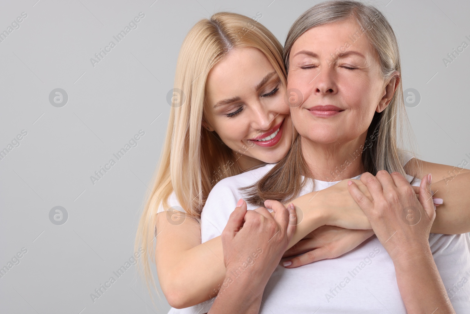 Photo of Family portrait of young woman and her mother on light grey background. Space for text